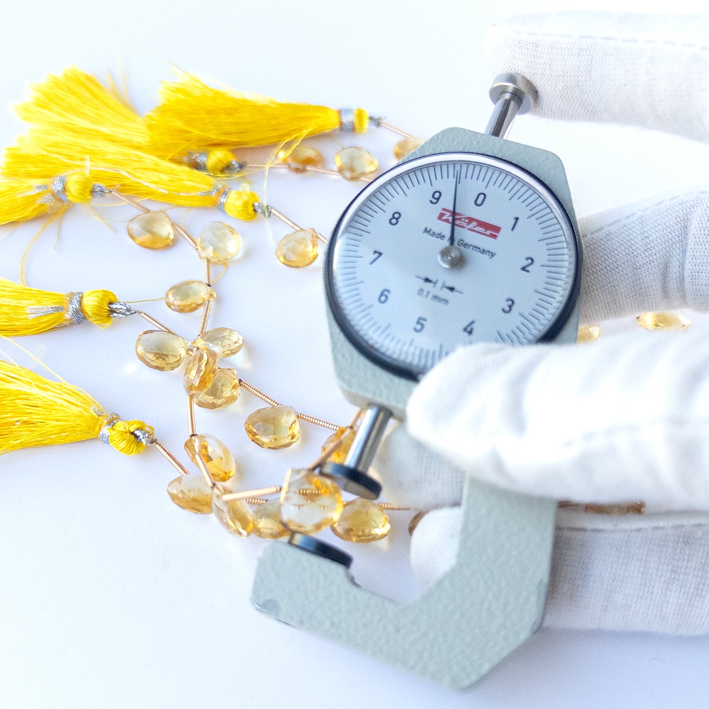 A dial gauge measures the Citrine faceted briolette 9.5–10mm gemstone.