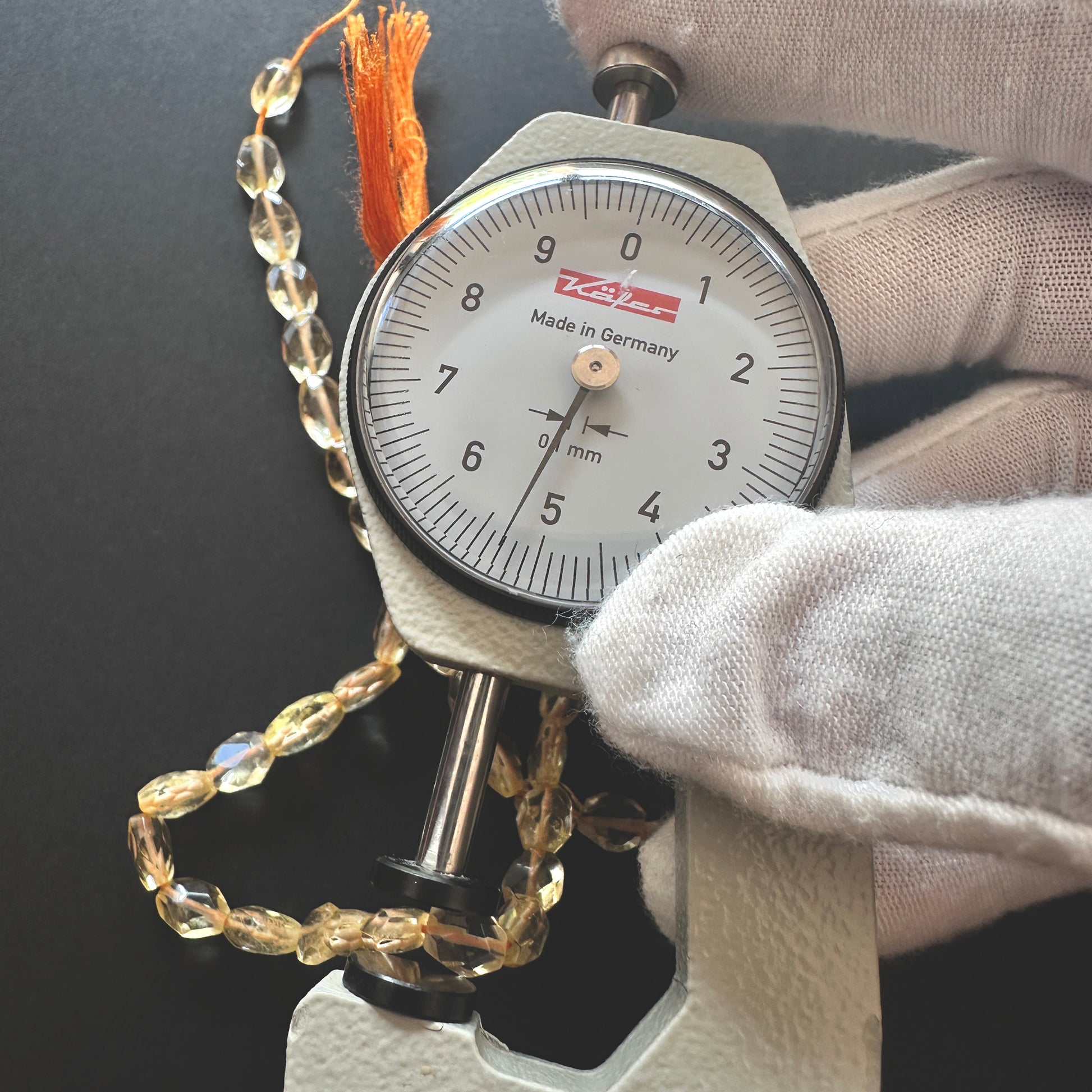 A dial gauge measures the Citrine faceted oval gemstone's breath.