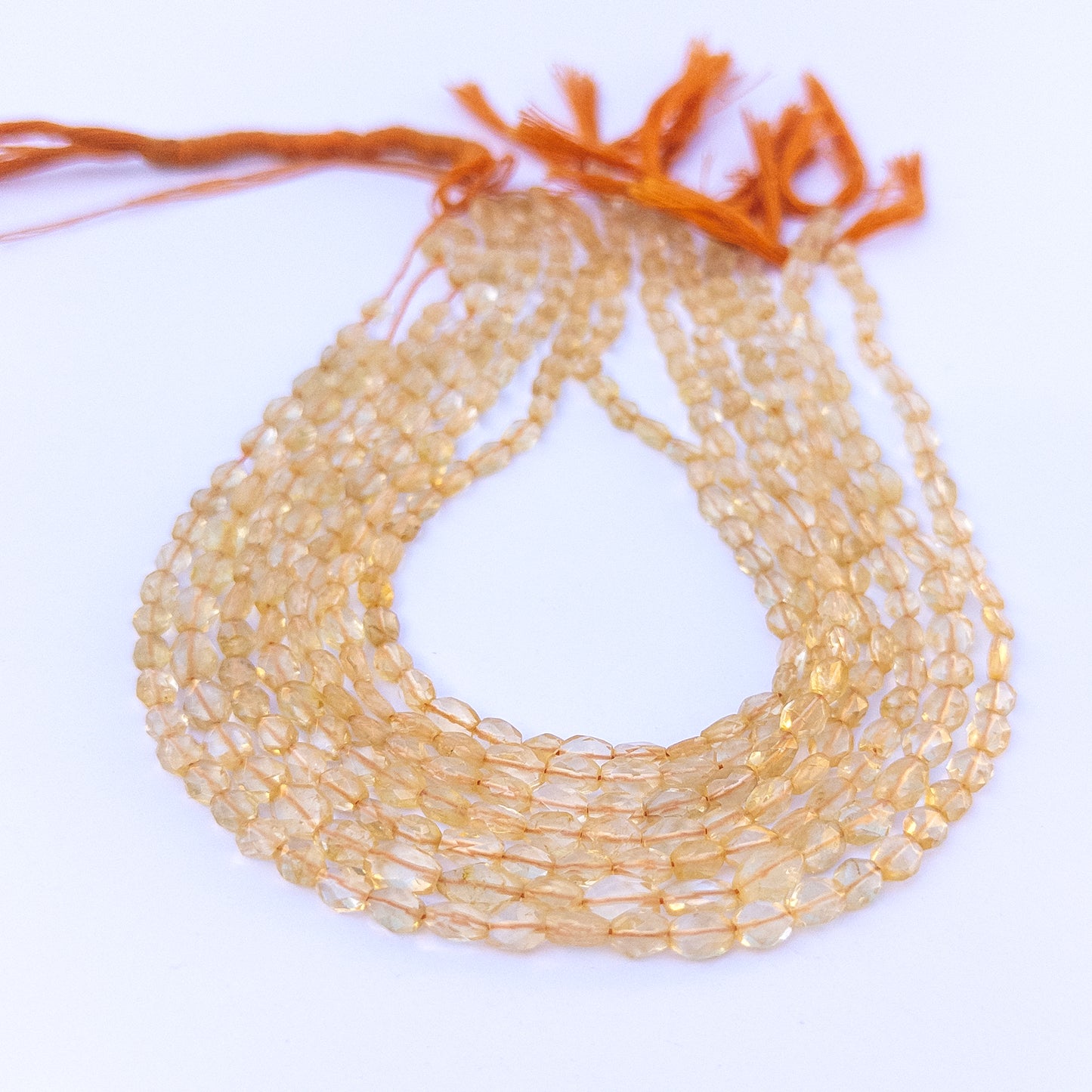 Citrine faceted oval beads in 4.7–6mm sizes arranged in a strand, showing warm golden tones for handmade jewellery components.