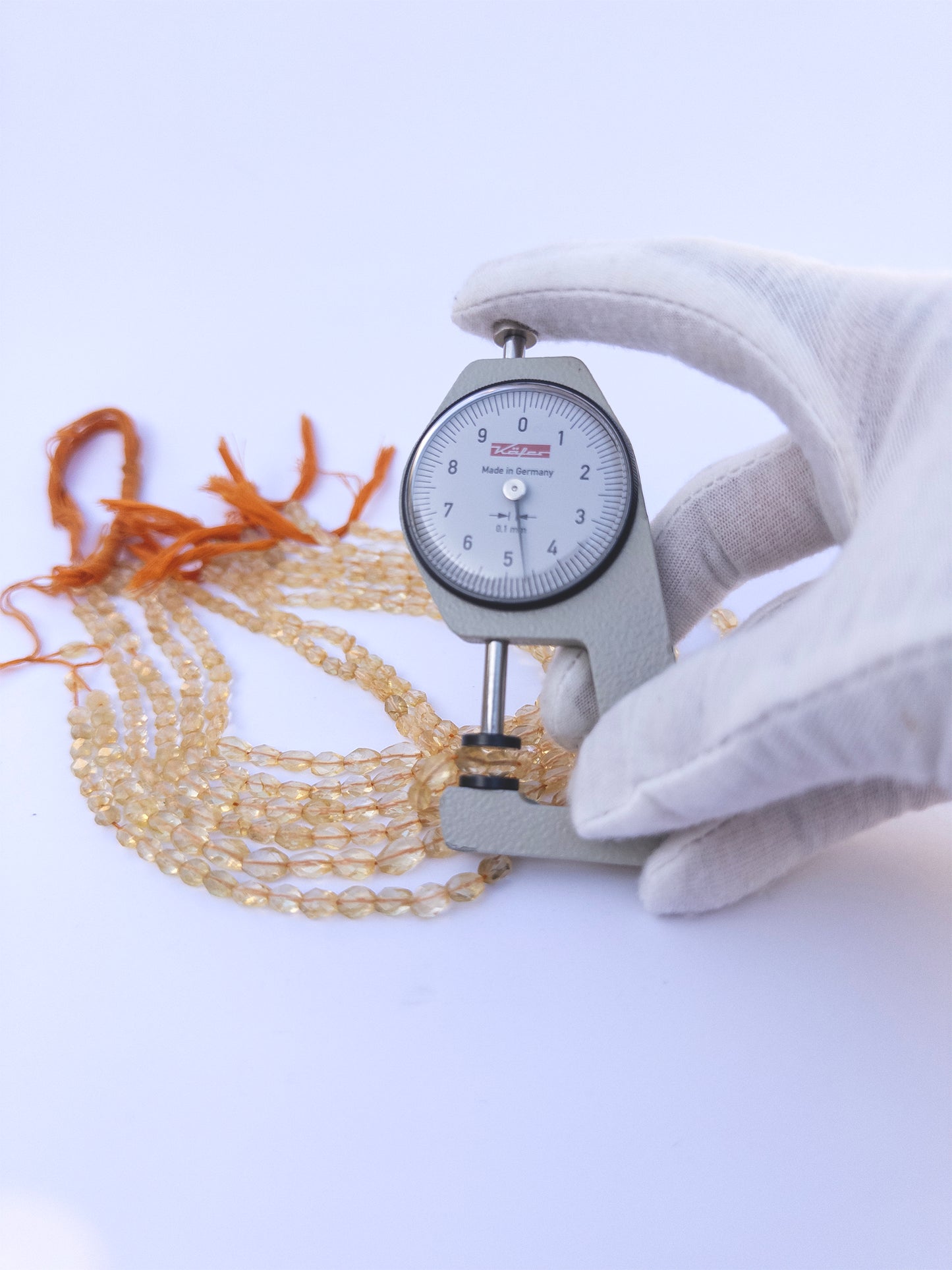 A dial gauge measures the Citrine Faceted Oval 4.7–6mm gemstone.