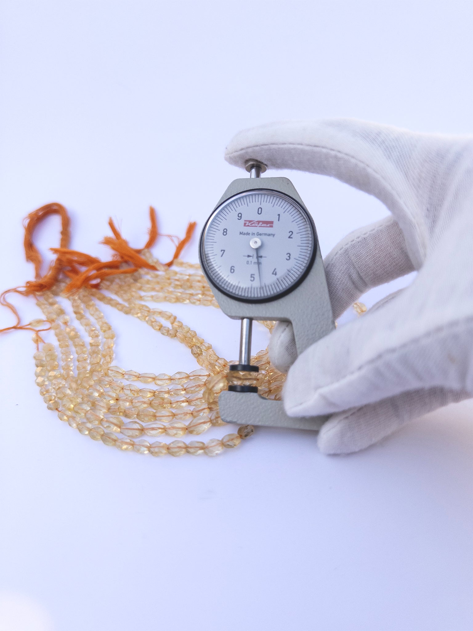 A dial gauge measures the Citrine Faceted Oval 4.7–6mm gemstone.