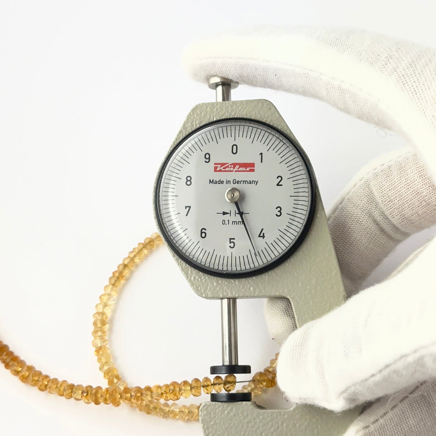 A dial gauge measures the Citrine faceted rondelle 4–4.5mm gemstone.