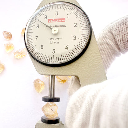 A dial gauge measures the Citrine rough cut 8mm gemstone.