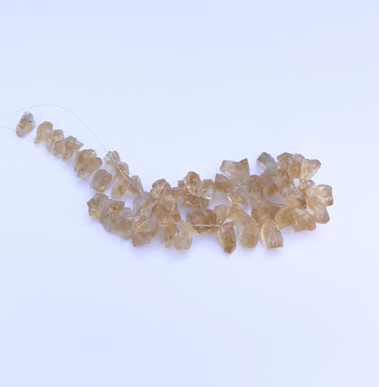  Close-up of 57 Citrine stone beads featuring drilled holes and raw crystal texture. 