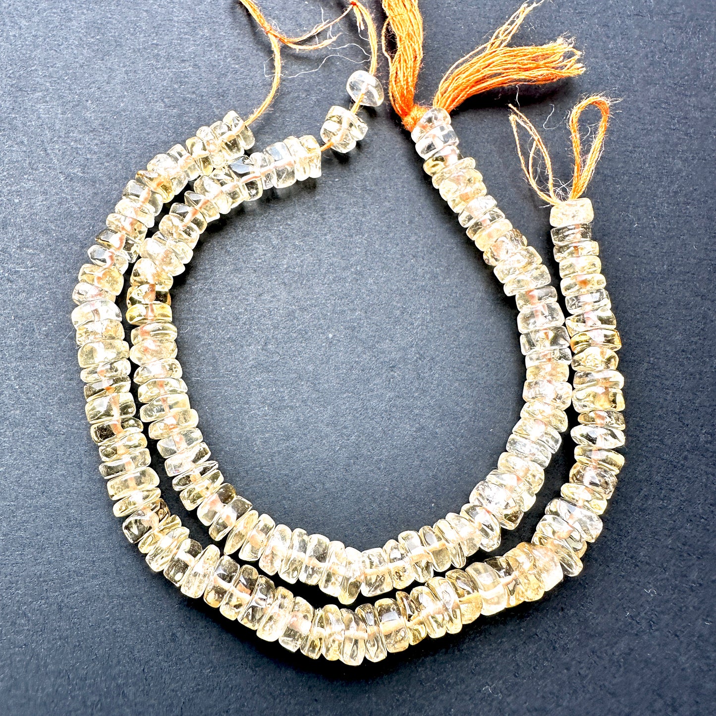 Citrine smooth wheel beads with golden yellow tones arranged on a 16cm strand for jewellery making.