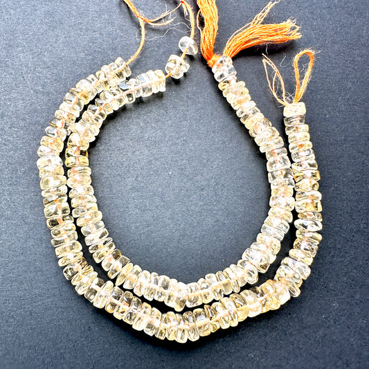 Citrine smooth wheel beads with golden yellow tones arranged on a 16cm strand for jewellery making.