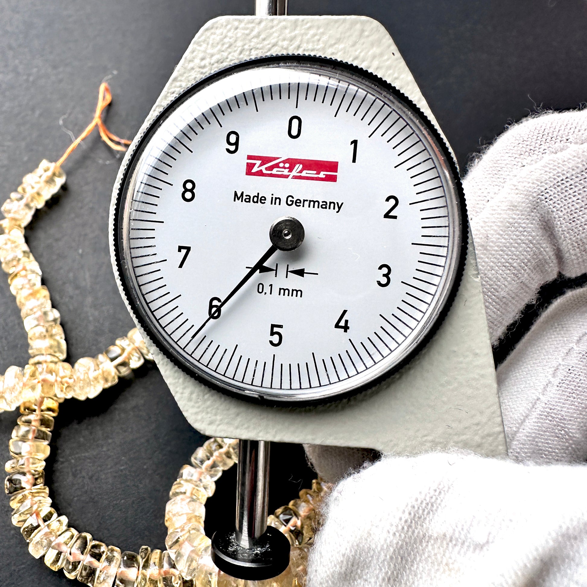 A dial gauge measures the Citrine smooth wheel 6mm gemstone.