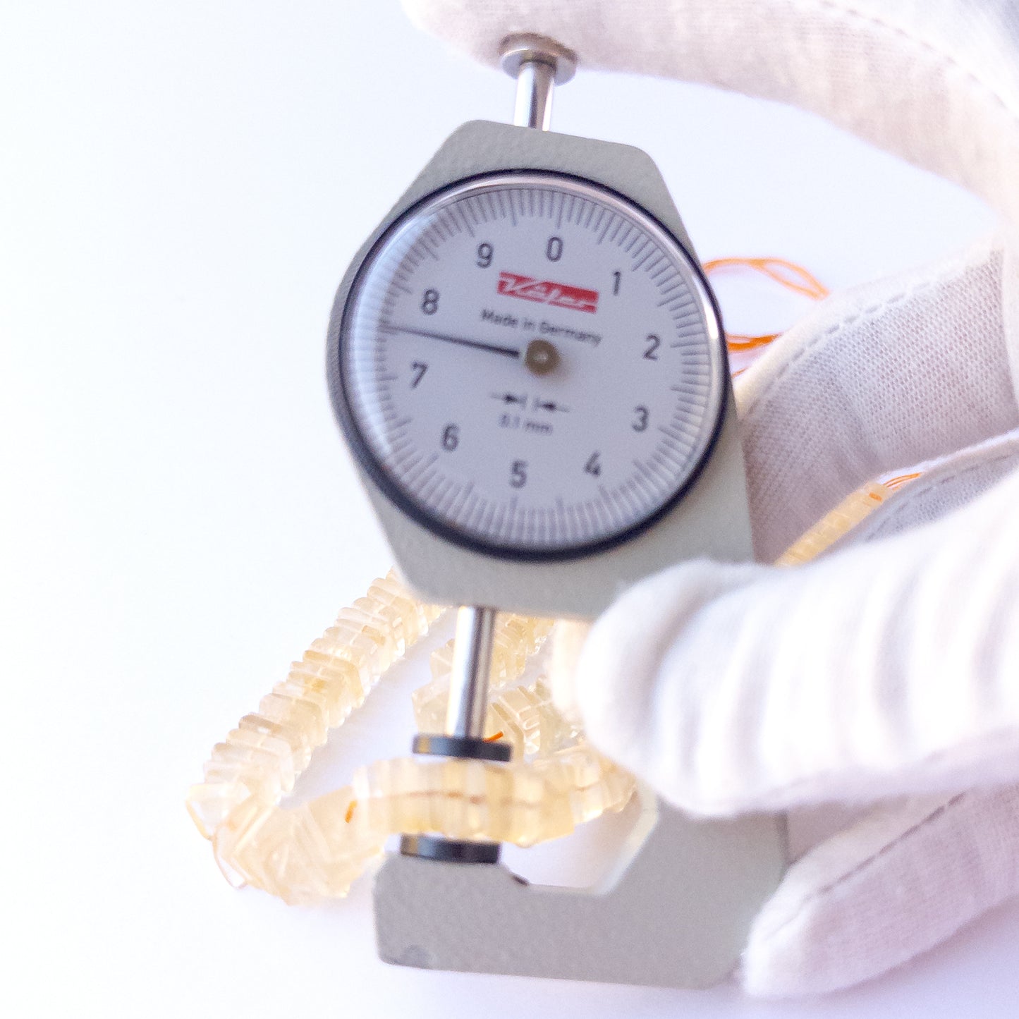 A dial gauge measures the Citrine square heishi 6.5–9mm gemstone.