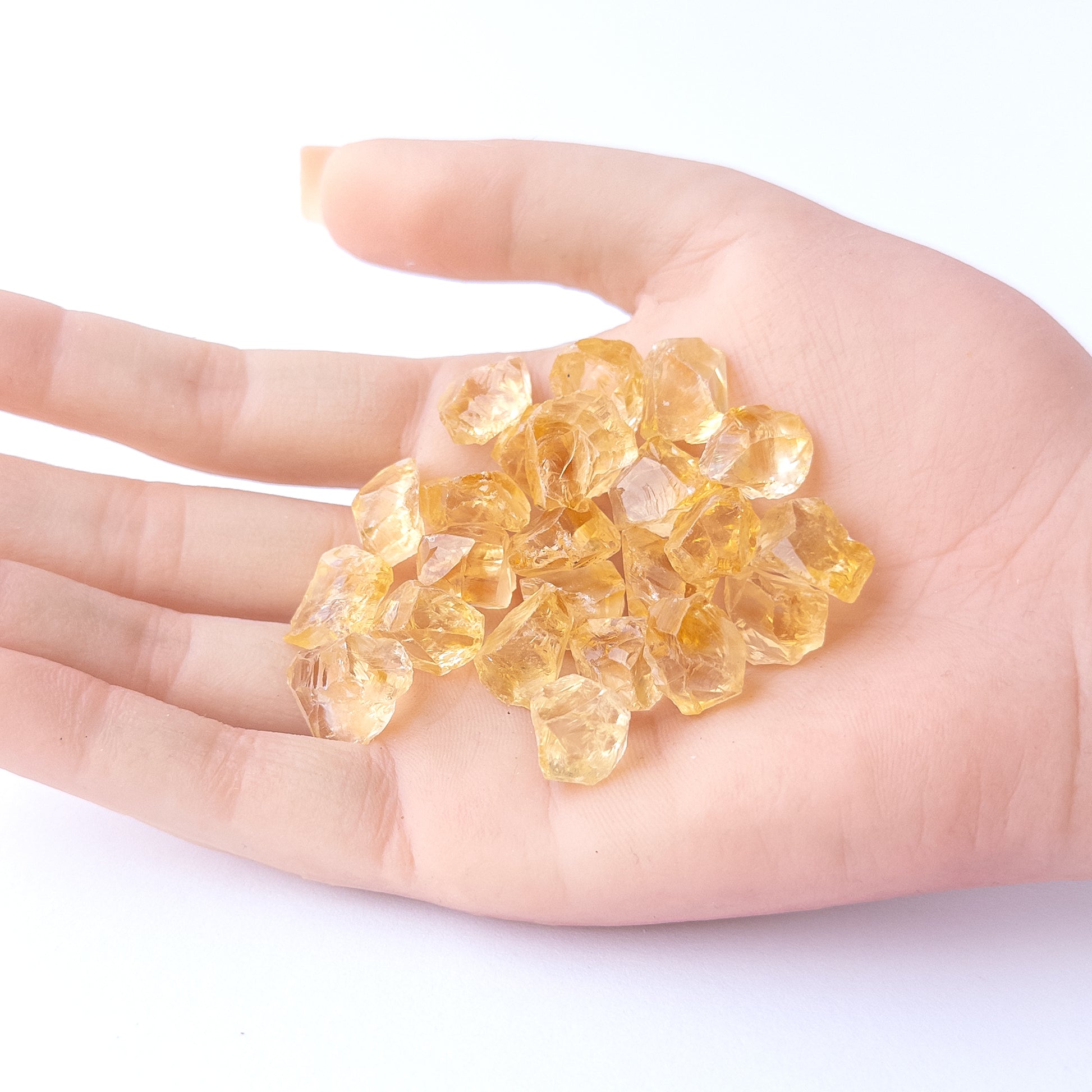 A person holds delicate pieces of Citrine rough, showcasing their natural design.
