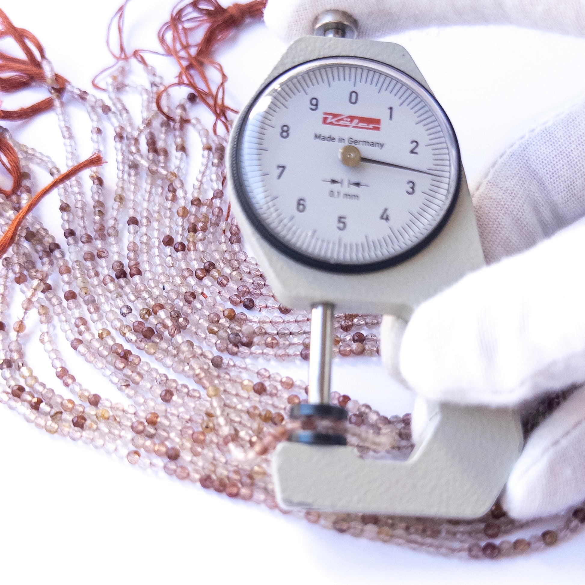 A dial gauge measures the Copper Rutile faceted rondelle 2.7mm gemstone.