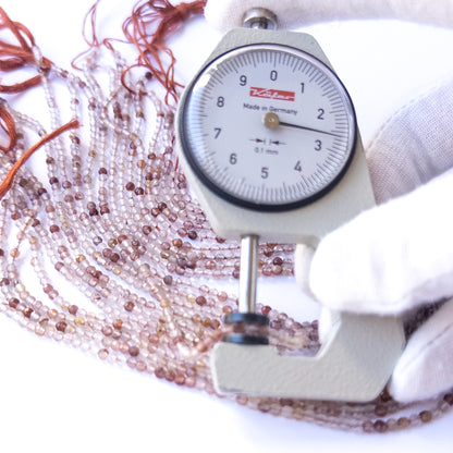 A dial gauge measures the Copper Rutile faceted rondelle 2.7mm gemstone.