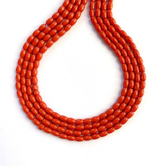 Close-up of coral drum beads in warm reddish tones on a 35cm strand.