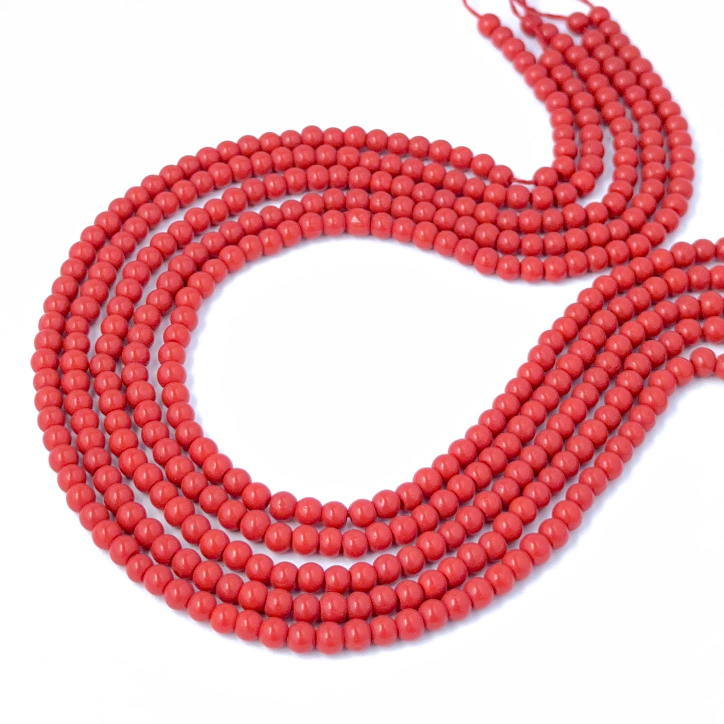 Taiwan Coral smooth round beads displayed on a 35cm strand to highlight their even sizing and rich tone.
