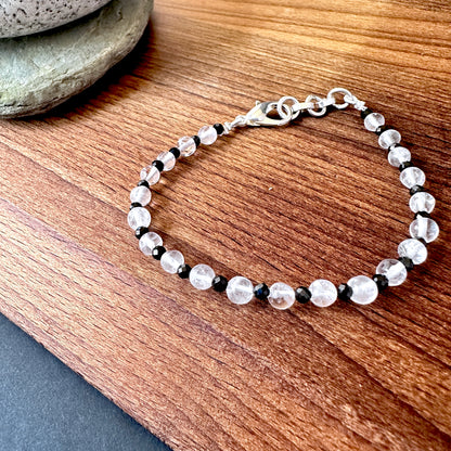 Close-up of crystal and black spinel bracelet featuring polished round stone beads, shimmering contrast and elegant shine.