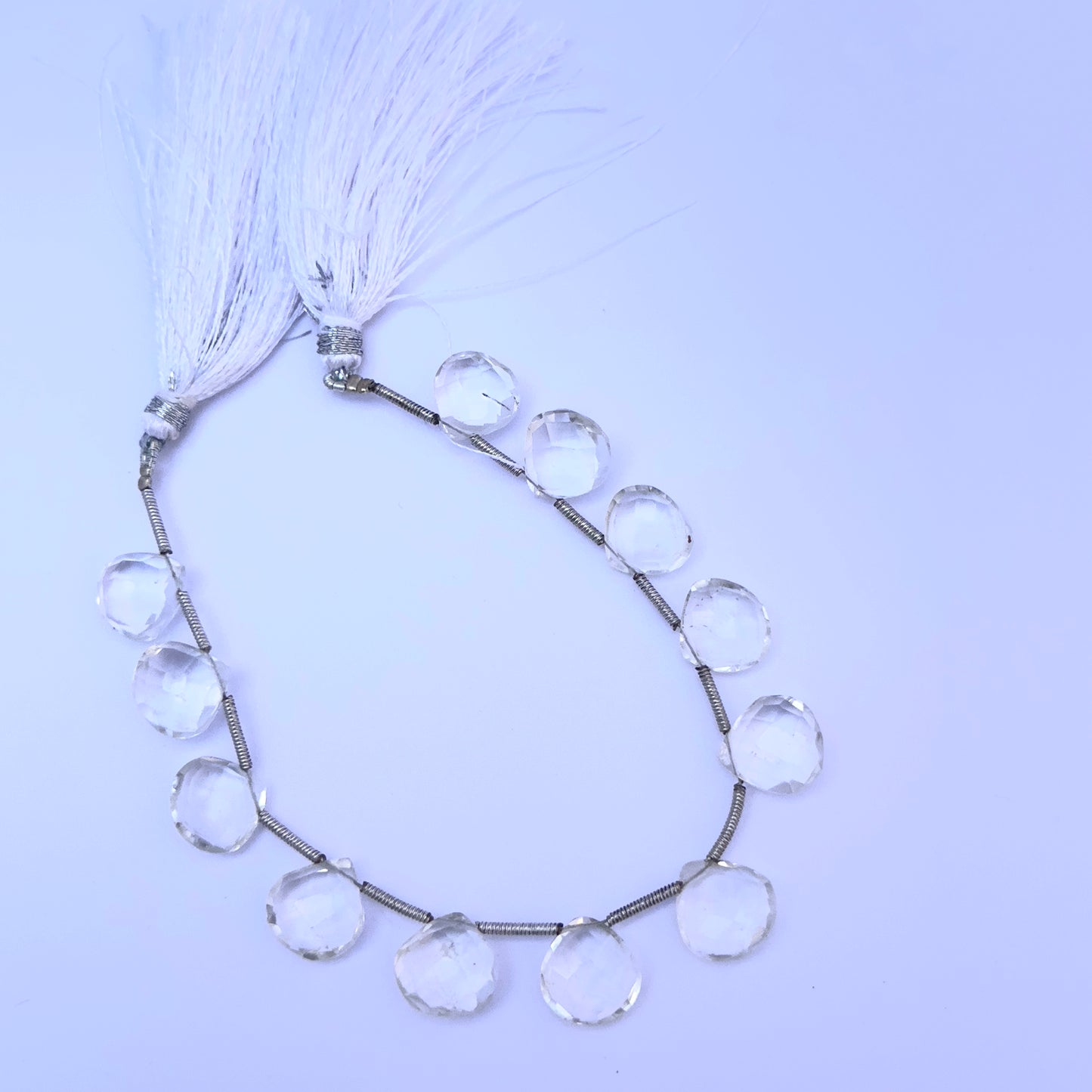 Crystal gemstone beads laid flat to highlight their faceted surface and heart briolette shape.