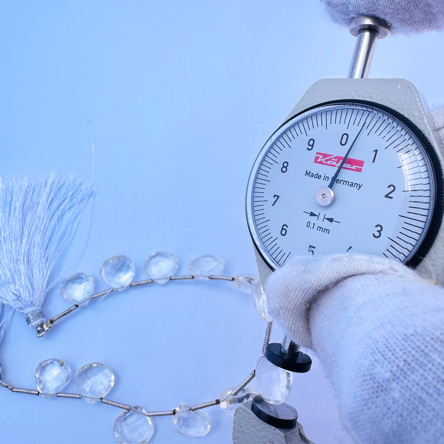 A dial gauge measures the Crystal faceted heart briolette 10.3–11mm gemstone.