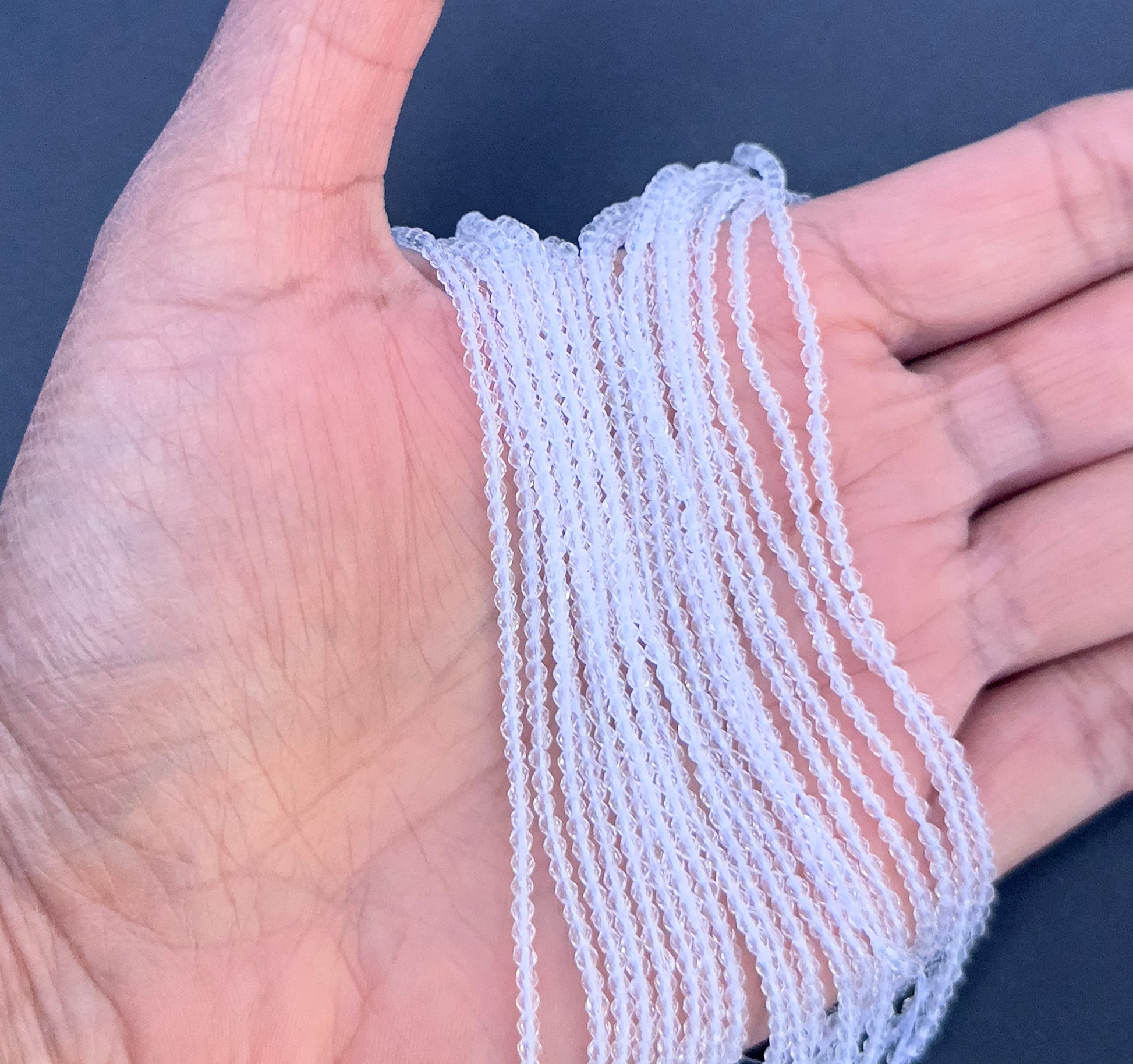 A person holds delicate strands of Crystal beads, showcasing their faceted design.