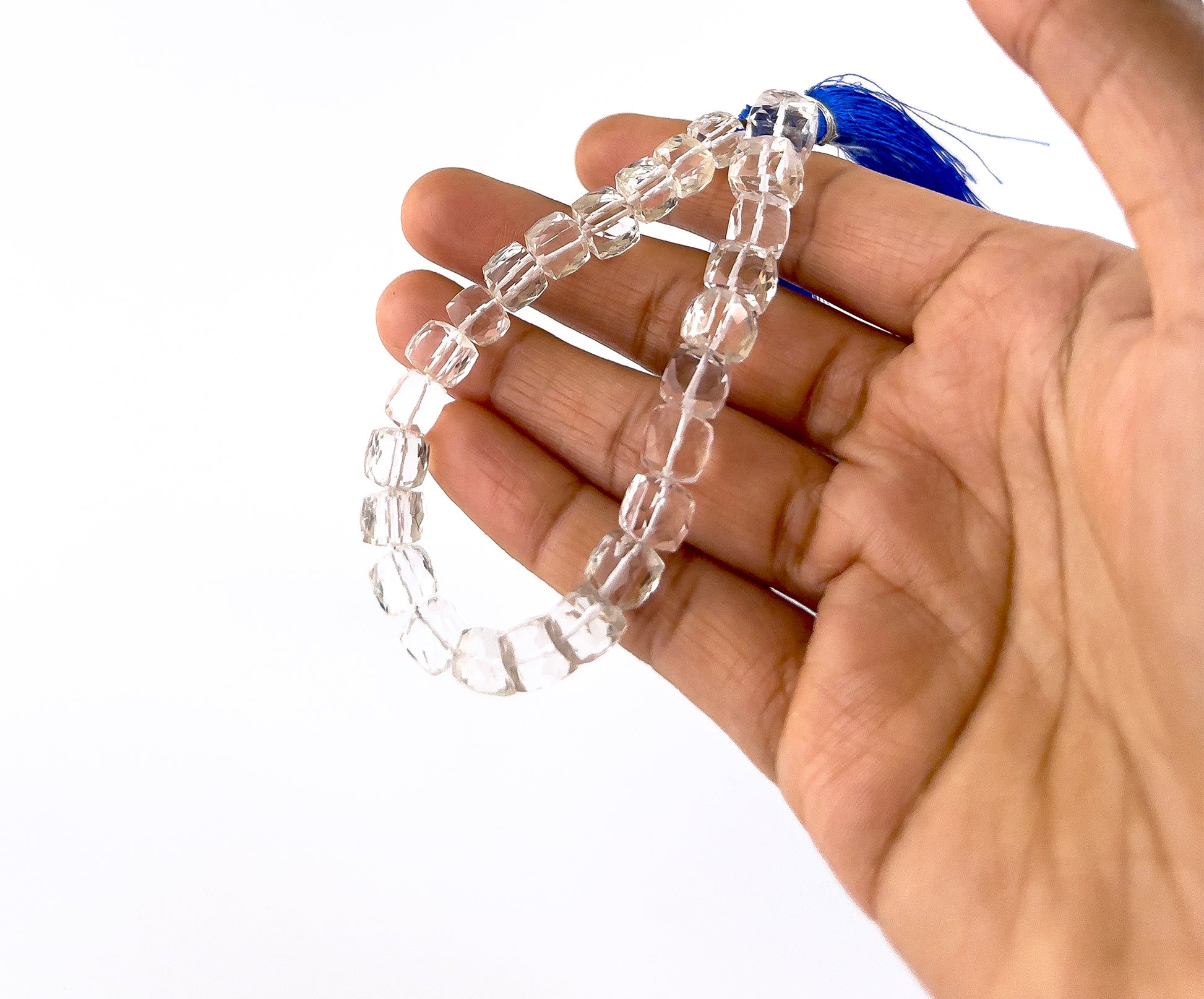 A person holds crystal smooth square beads, showing their polished shape and clear transparency.