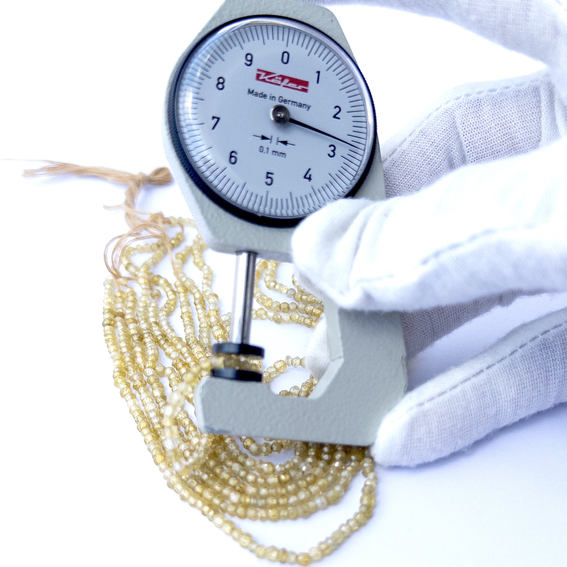 A dial gauge measures the Cubic Zirconia faceted rondelle 2.5–2.7mm gemstone.