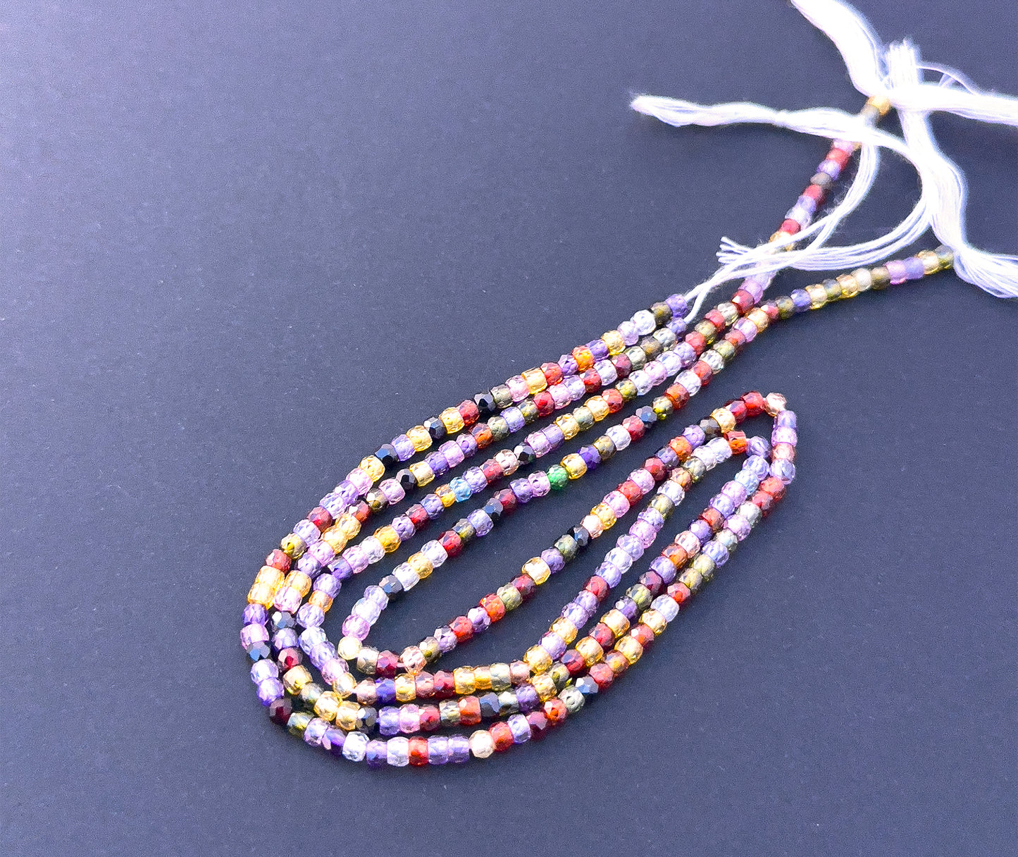 Close-up of sparkling Cubic Zirconia stone beads with precision faceted rondelle cut. Natural gemstone beads for DIY jewellery featuring Cubic Zirconia in 3.1mm faceted rondelle shape.