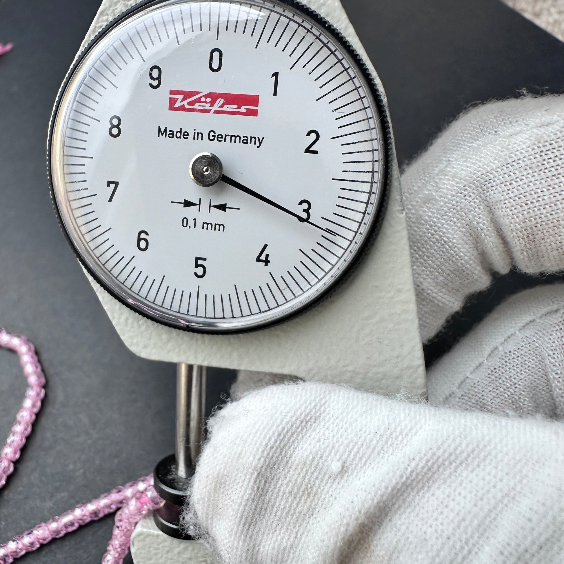 A dial gauge measures the Pink Cubic Zirconia faceted rondelle 3.1mm bead.