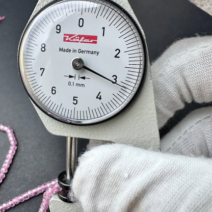 A dial gauge measures the Pink Cubic Zirconia faceted rondelle 3.1mm bead.