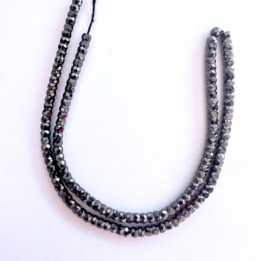 Black Cubic Zirconia rondelle beads with faceted cut and glossy finish arranged neatly on a 36cm strand.