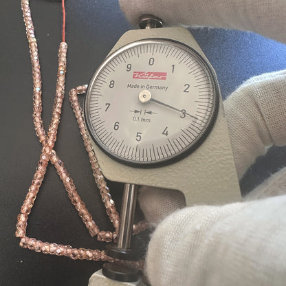 A dial gauge measures the Cubic Zirconia faceted rondelle 3mm gemstone.