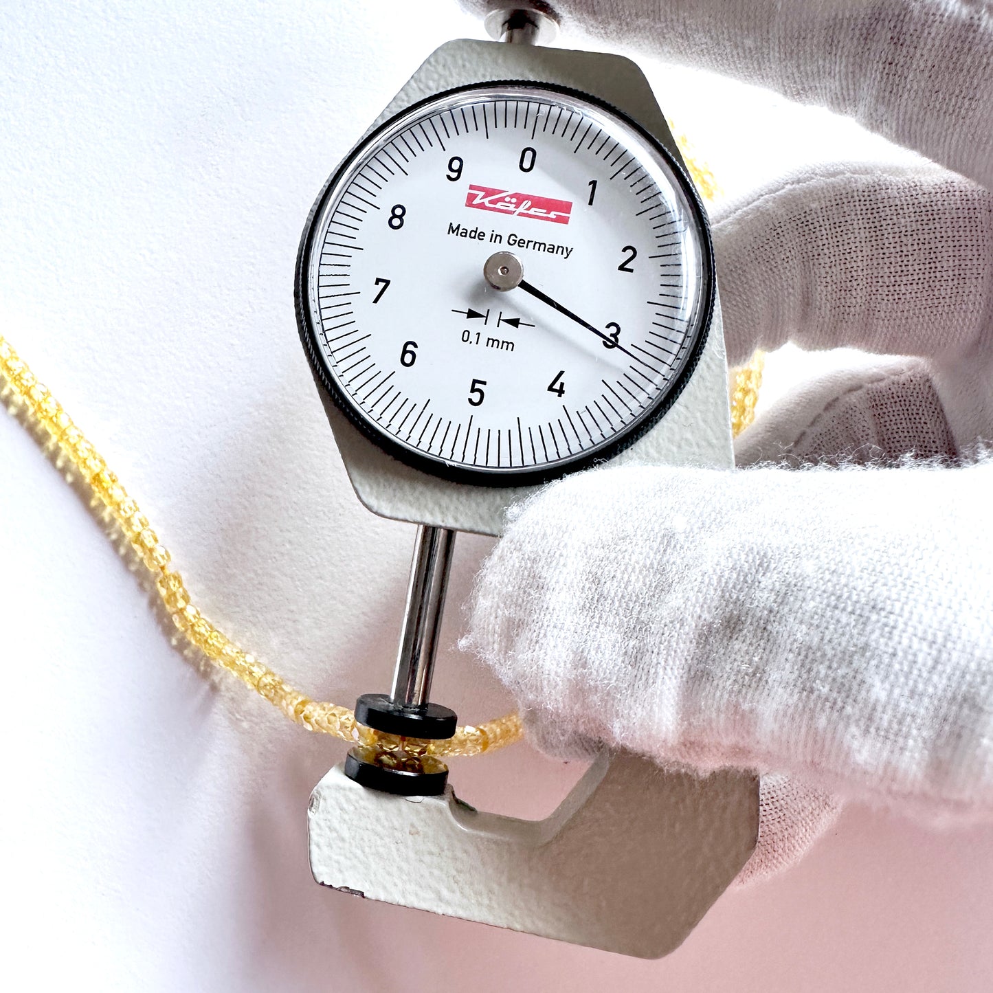 A dial gauge measures the Yellow Cubic Zirconia faceted rondelle 3mm gemstone.