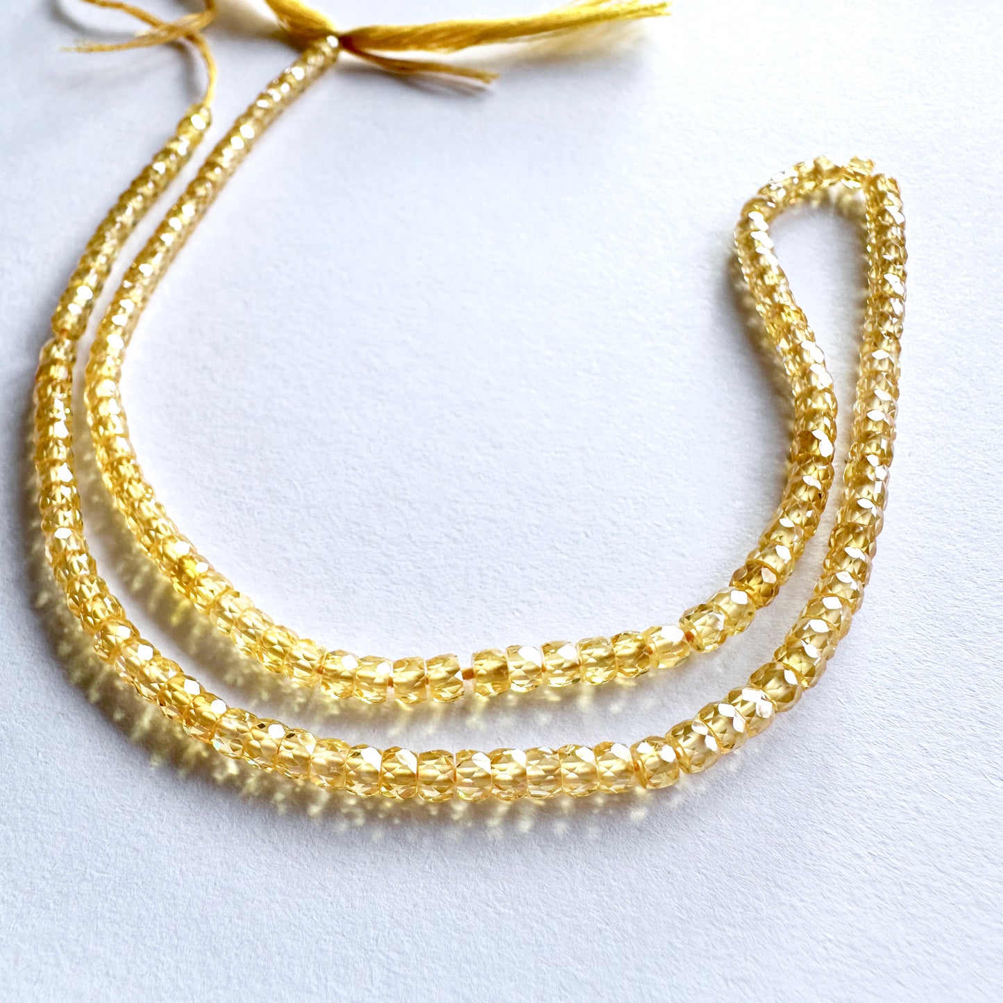 Delicate strands of Yellow Cubic Zirconia beads, showcasing their smooth design.