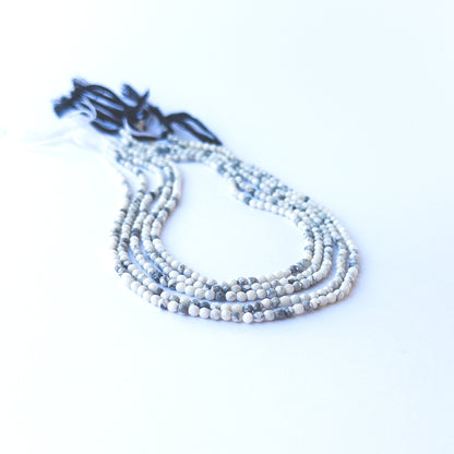 Dendrite Opal faceted rondelle beads displaying black‑and‑white inclusions and polished surfaces.