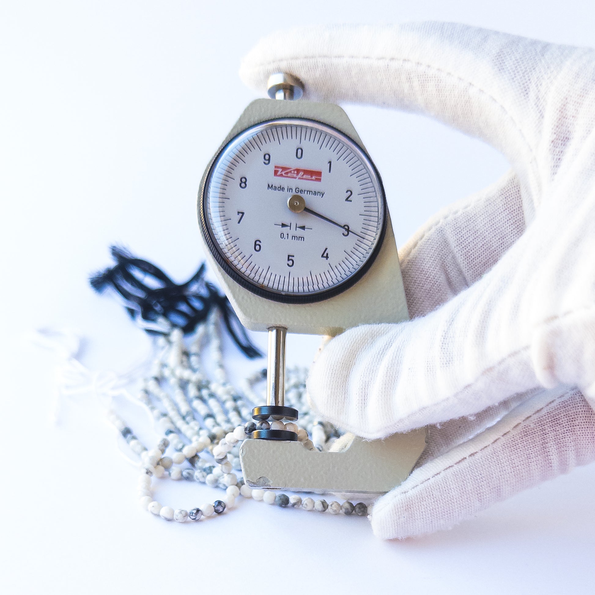 A dial gauge measures the Dendrite Opal faceted rondelle 3.1mm gemstone.