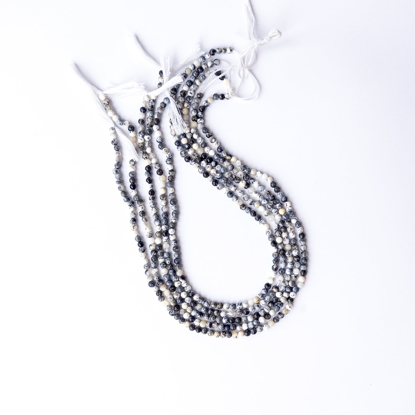 A dial gauge measures the Dendrite Opal smooth round 3.6mm gemstone bead.