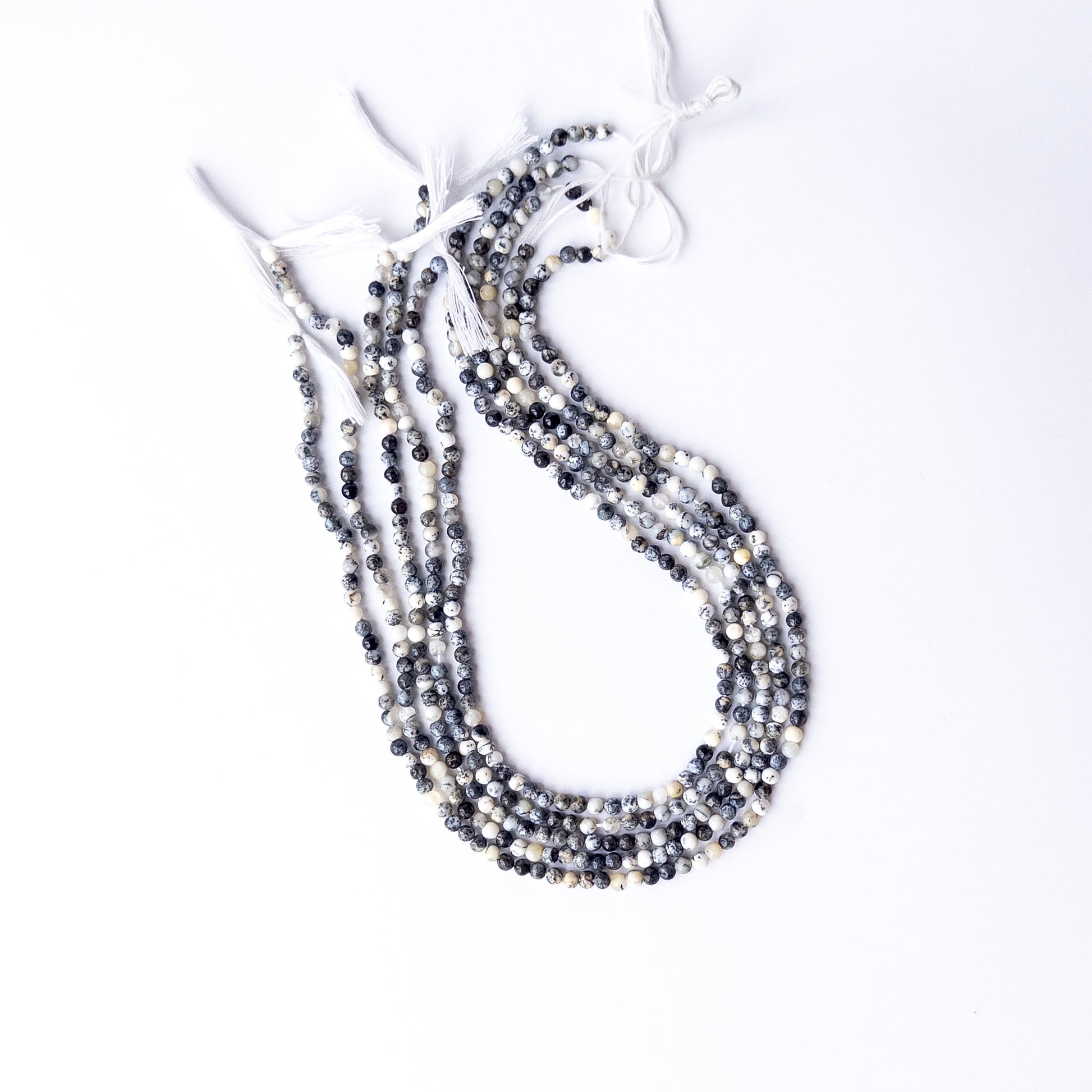 A dial gauge measures the Dendrite Opal smooth round 3.6mm gemstone bead.