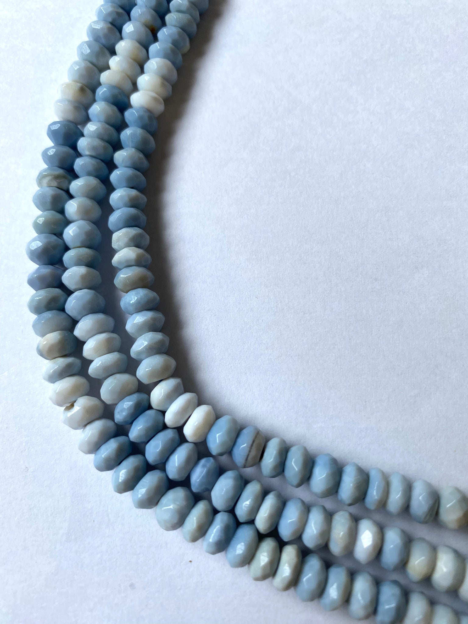 Close-up of Denim Blue Opal beads highlights their expert faceting and striking opalescent glow.