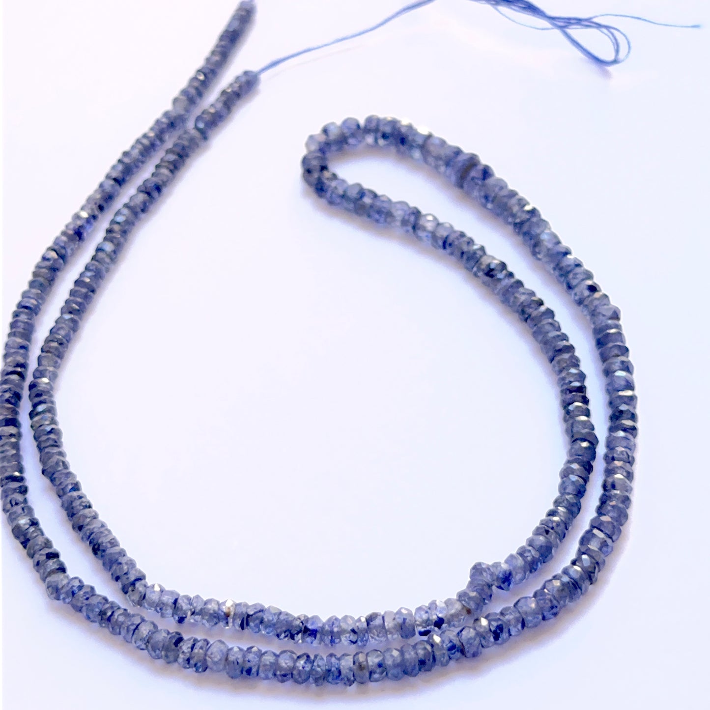 Blue Sapphire faceted rondelle 3–4mm beads arranged to display uniform shape and vivid sapphire hues.

