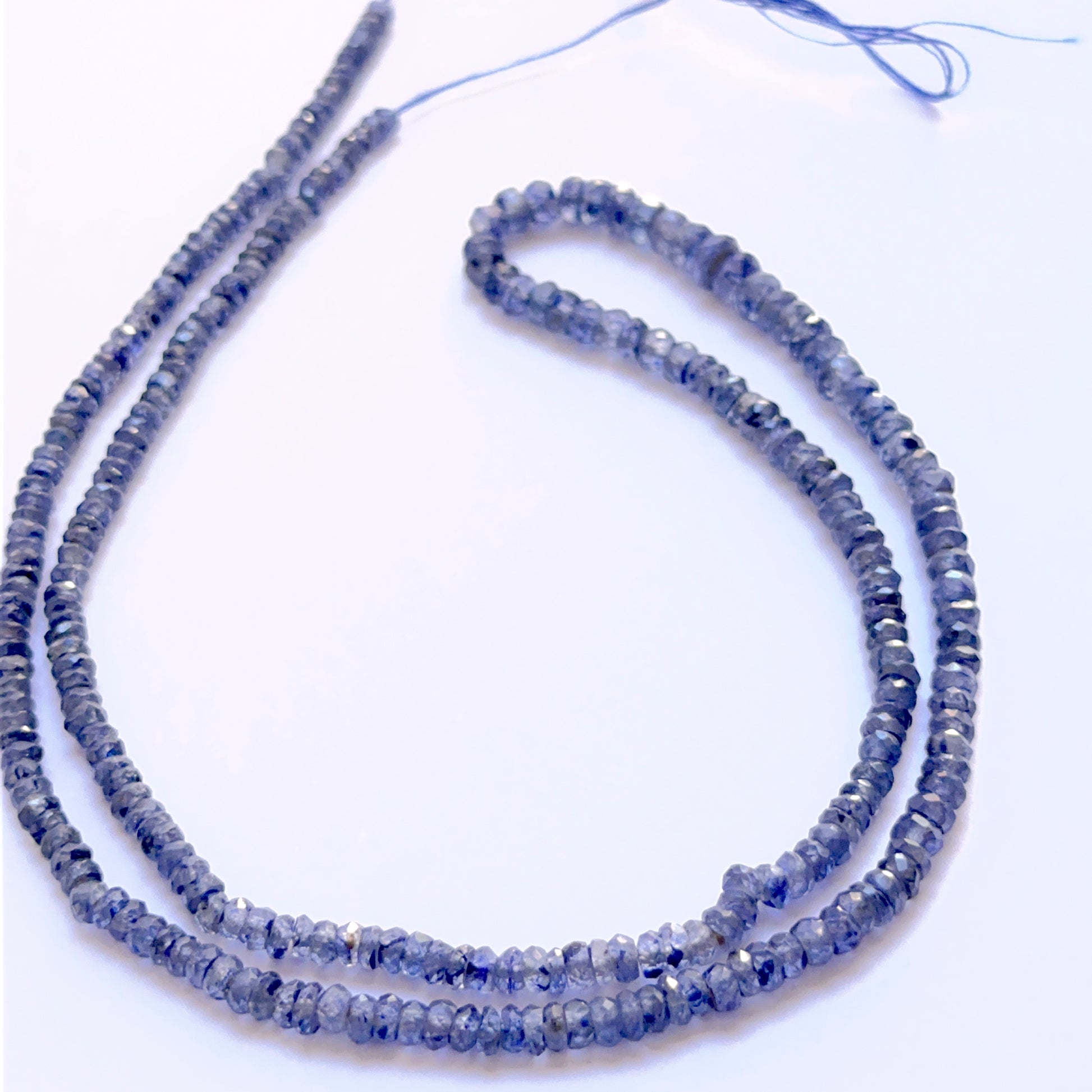 Blue Sapphire faceted rondelle 3–4mm beads arranged to display uniform shape and vivid sapphire hues.

