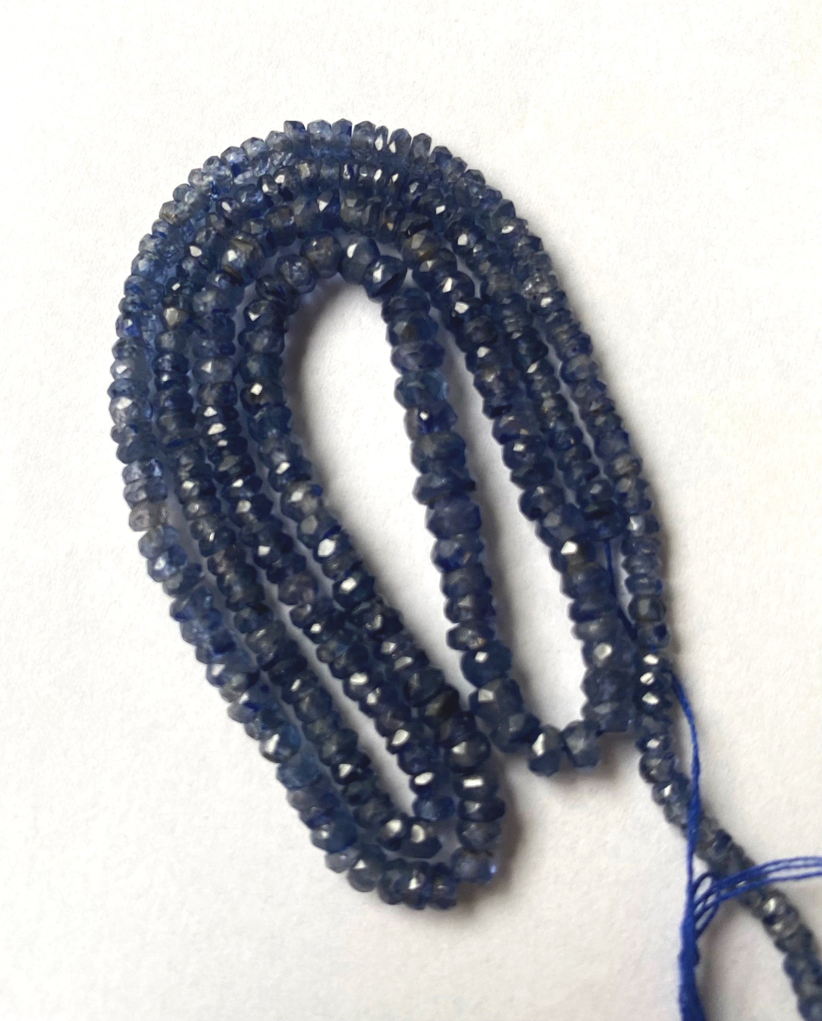 Denim Blue Sapphire faceted rondelle beads in deep indigo tones neatly arranged on a 43cm strand.