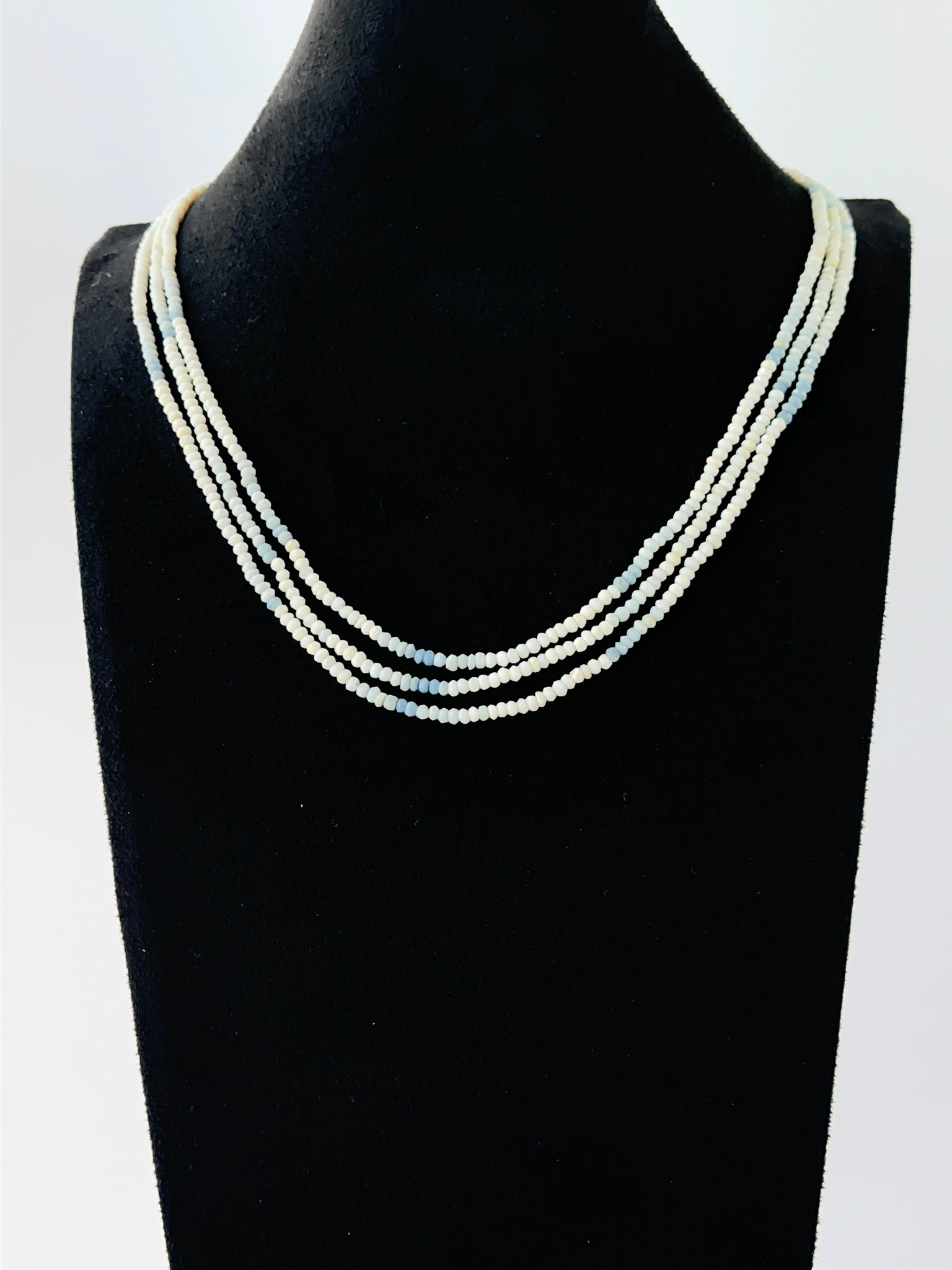 Multi‑strand denim opal necklace with faceted rondelle beads arranged in soft graduated layers.