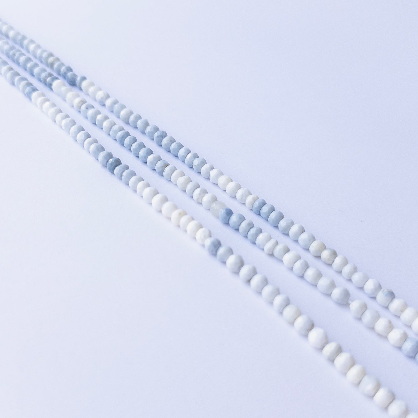 Denim Opal faceted rondelle beads displayed in multiple strands, showing consistent sizing and subtle colour shifts.