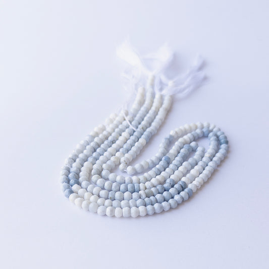 Strands of Denim Opal faceted rondelle gemstone beads arranged neatly, showcasing their fine cut and natural blue hues.