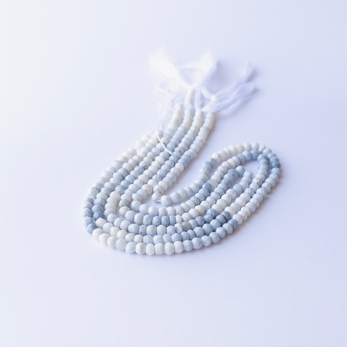 Genuine Denim Opal gemstone beads in faceted rondelle cut, displaying polish, texture, and natural beauty.