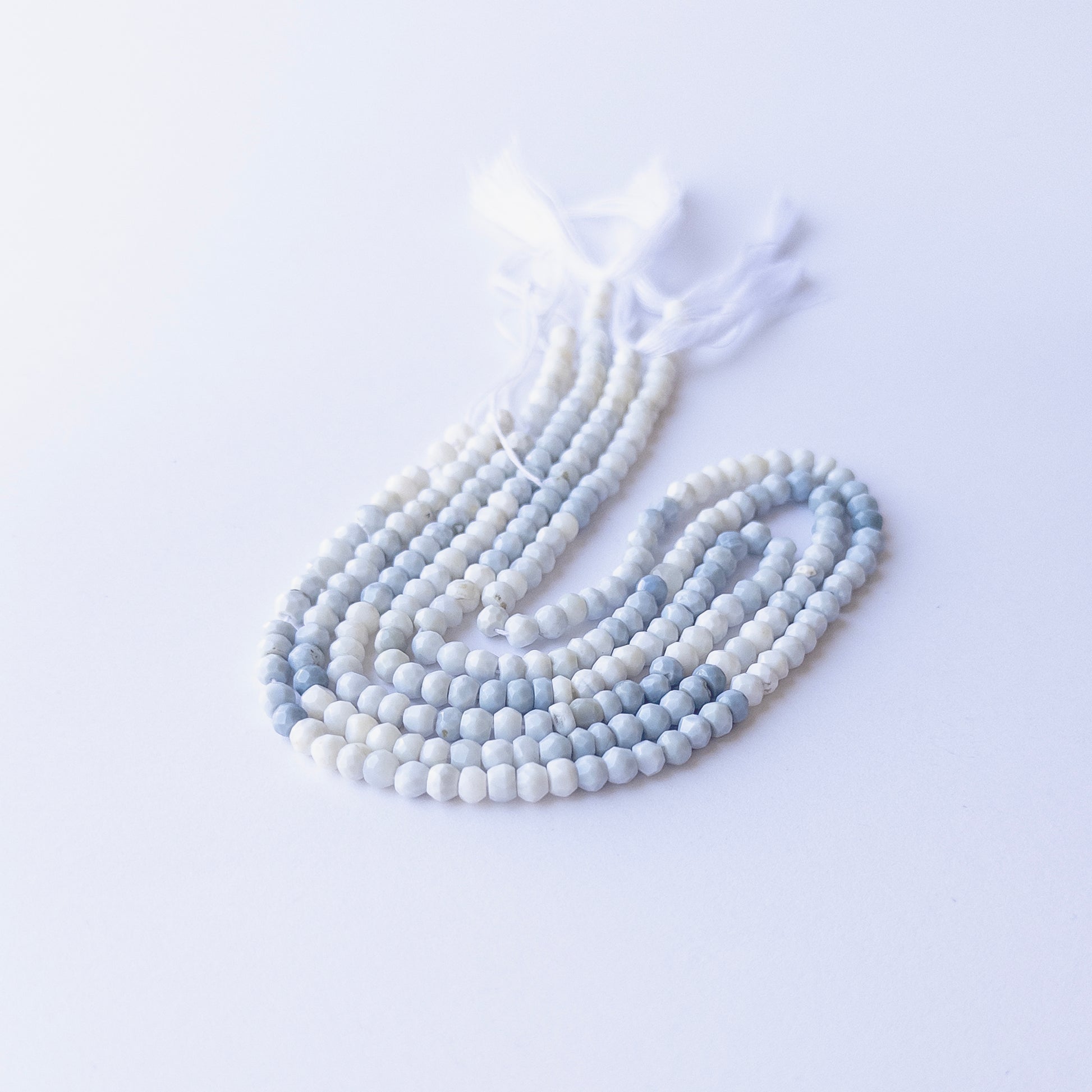 Genuine Denim Opal gemstone beads in faceted rondelle cut, displaying polish, texture, and natural beauty.