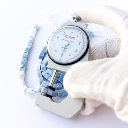 A dial gauge measures the Denim Opal smooth cube 5mm gemstone.