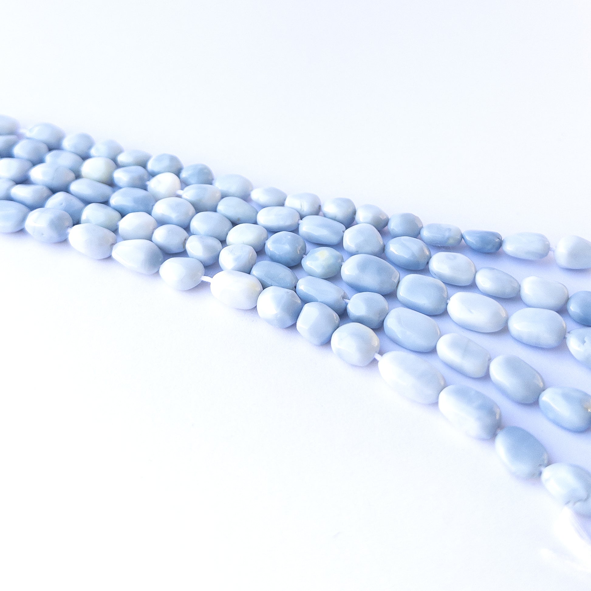 Handmade jewellery components featuring natural denim opal smooth tumbles with earthy blue tones.