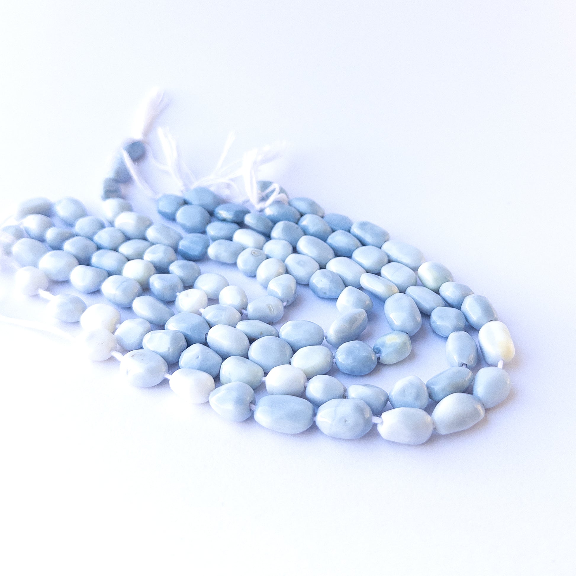Genuine stone beads in soft denim‑blue hues, featuring smooth tumbles for DIY jewellery making.