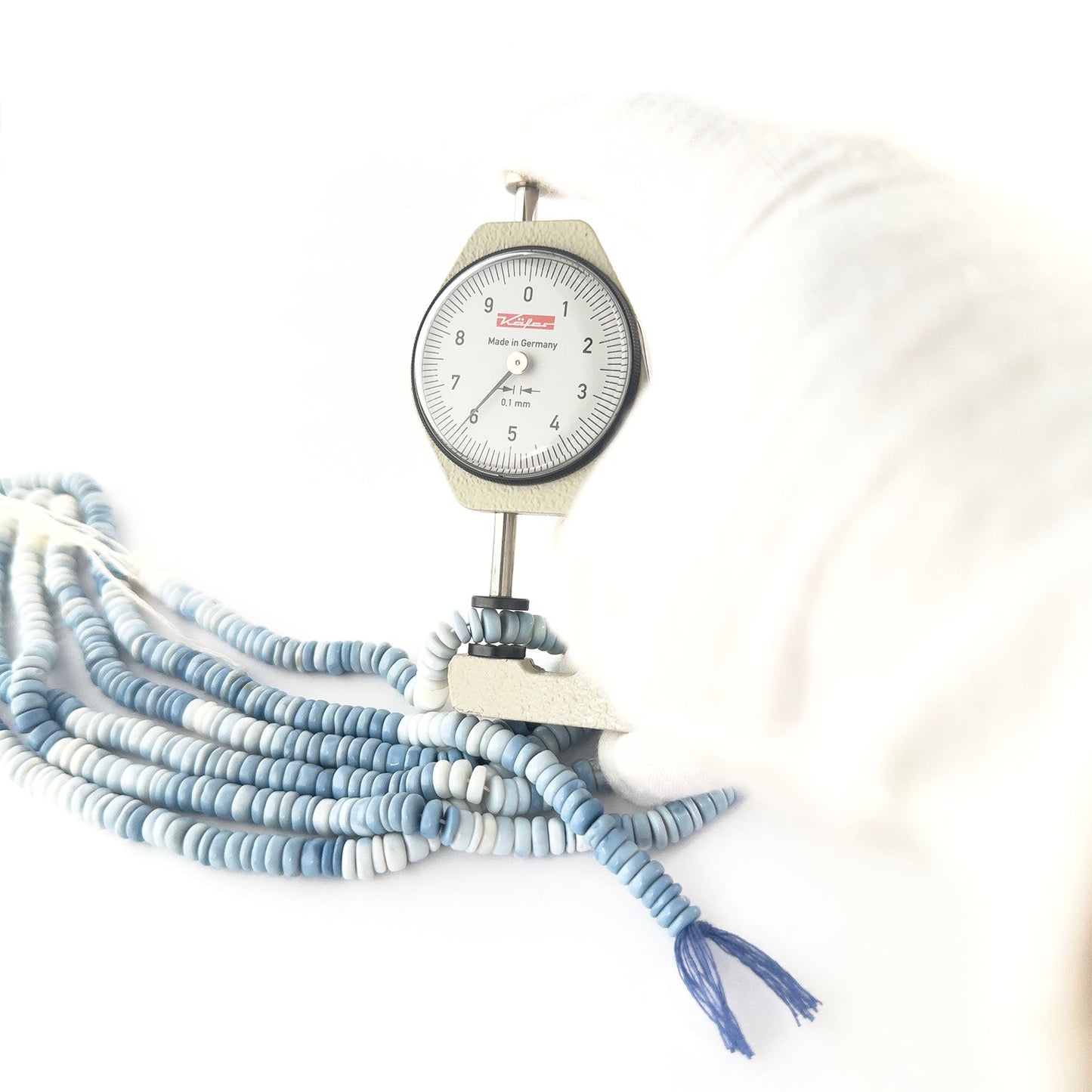 A dial gauge measures the Denim Opal smooth wheel 6–7mm gemstone.