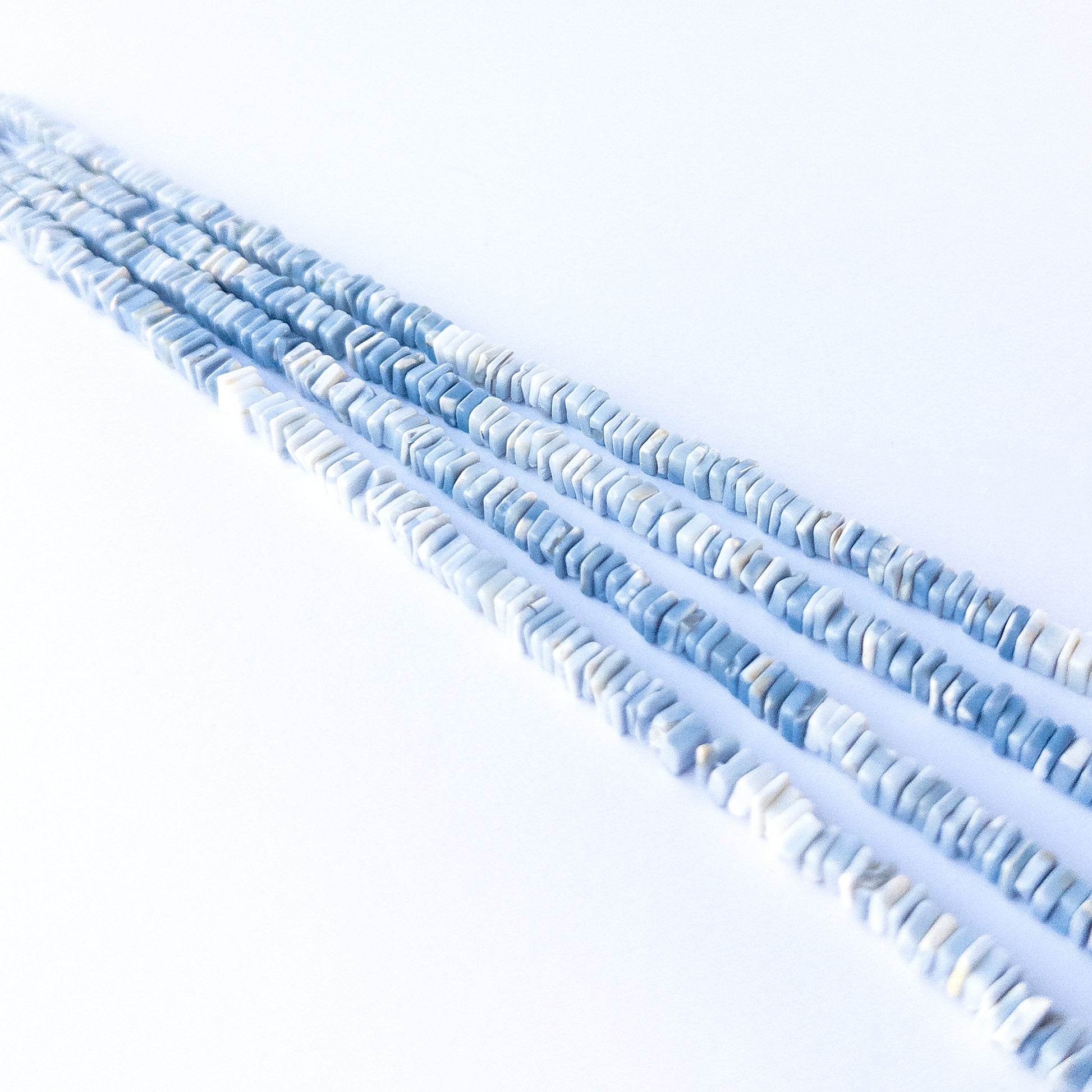 Handmade jewellery components featuring authentic Denim Opal square heishi beads with soft denim‑blue colour.