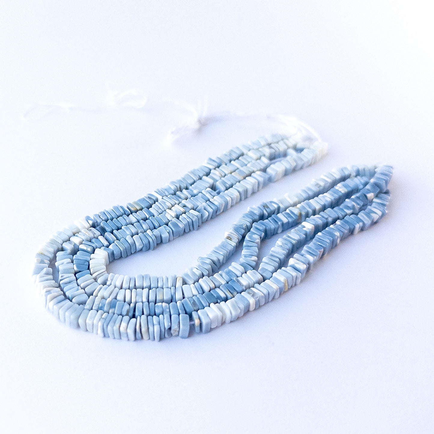 Close‑up of genuine Denim Opal square heishi beads showing their matte blue tone, shine and precise 4.5mm cut.