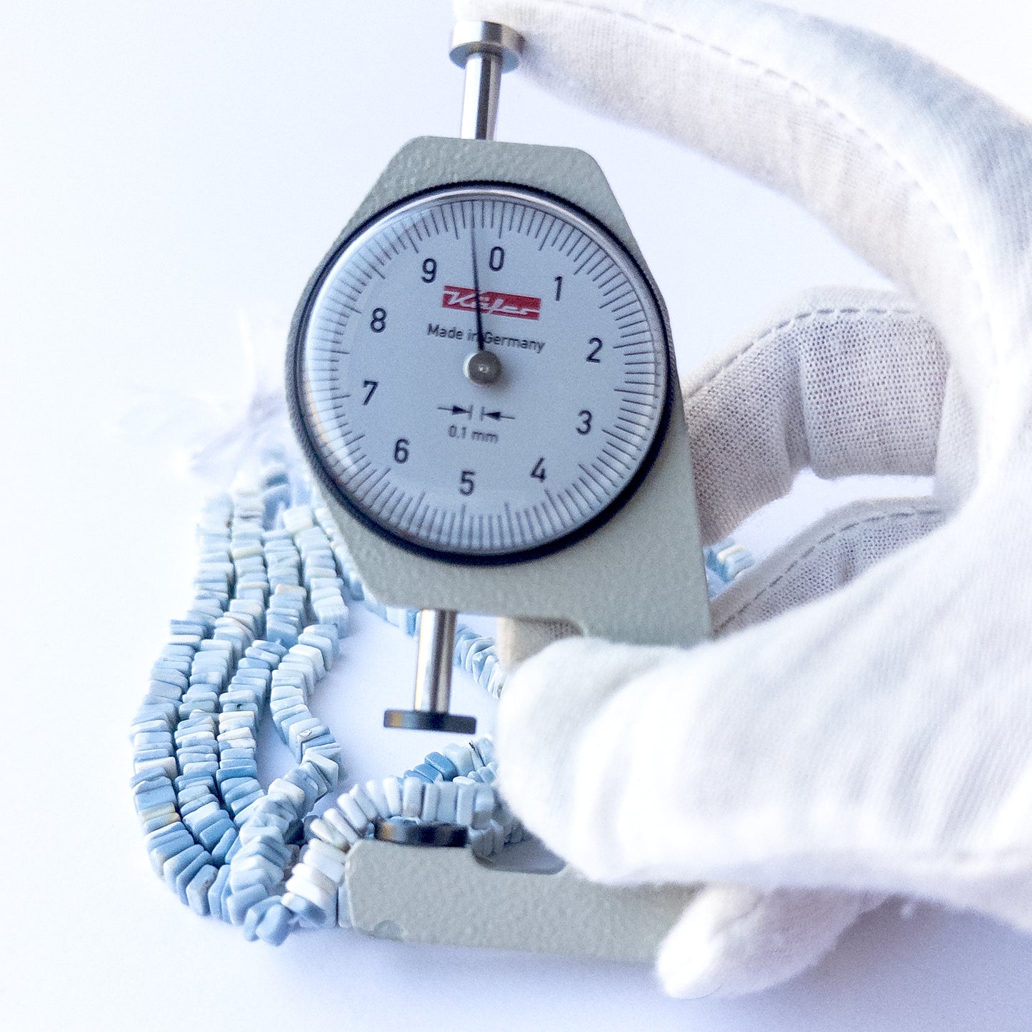 A dial gauge measures the Denim Opal square heishi 4.5mm gemstone.